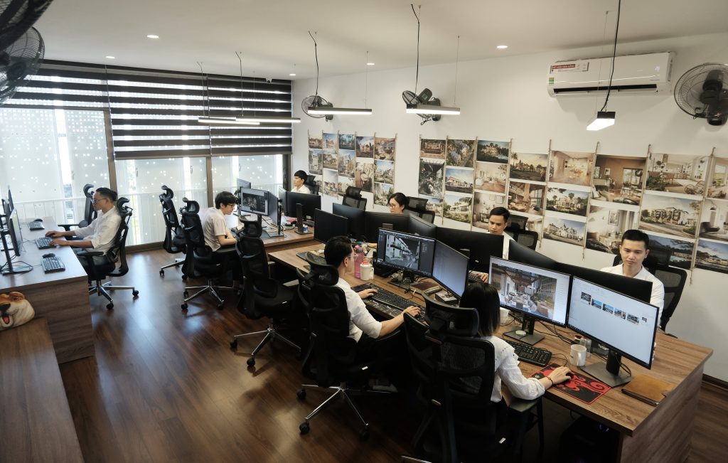 A vibrant studio environment in Vietnam, showing a team of outsourcing 3D rendering artists at their desks, each working on multiple monitors, likely collaborating on architectural visualization projects. The walls are adorned with various project renders and design inspirations, showcasing a productive 3D artist workspace.