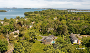Aerial 3D rendering (photomontage) of a large property with a house and pool, surrounded by dense green trees near the ocean.